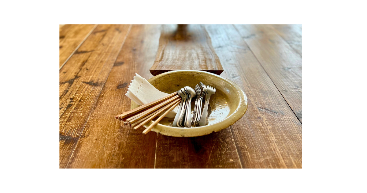 木のテーブルで全粒粉クッキーと季節の果物を囲み、穏やかな光の中でおやつをいただく親子の様子