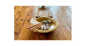 木のテーブルで全粒粉クッキーと季節の果物を囲み、穏やかな光の中でおやつをいただく親子の様子