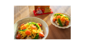 自然光の入る室内に桃の花と小さな雛人形を飾ったシンプルなひな祭りの空間