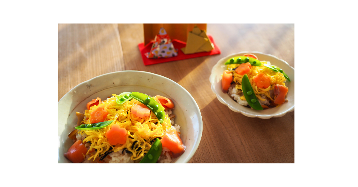 自然光の入る室内に桃の花と小さな雛人形を飾ったシンプルなひな祭りの空間